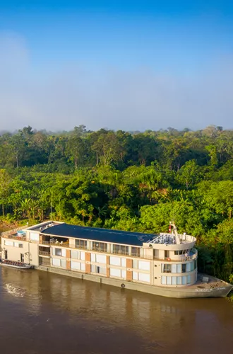 river cruise ship pulled up to the shore in a rainforest