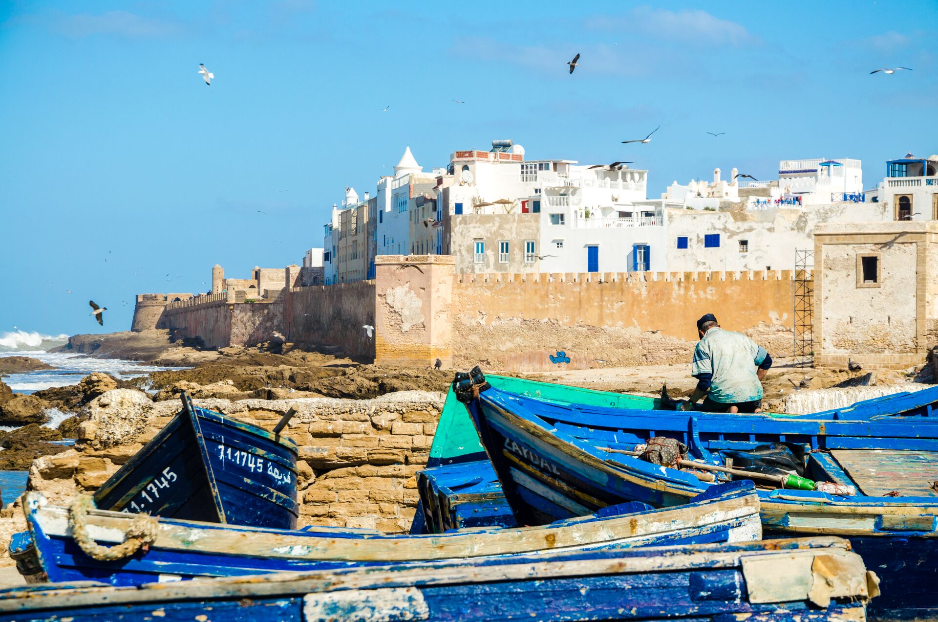 Site of a white city behind a wall with blue boats in the foreground