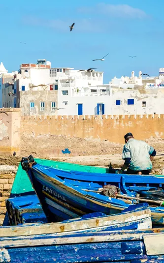 Site of a white city behind a wall with blue boats in the foreground