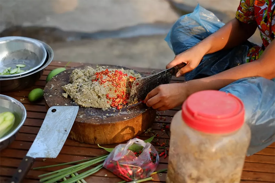 person curring chilli and adding it to a paste