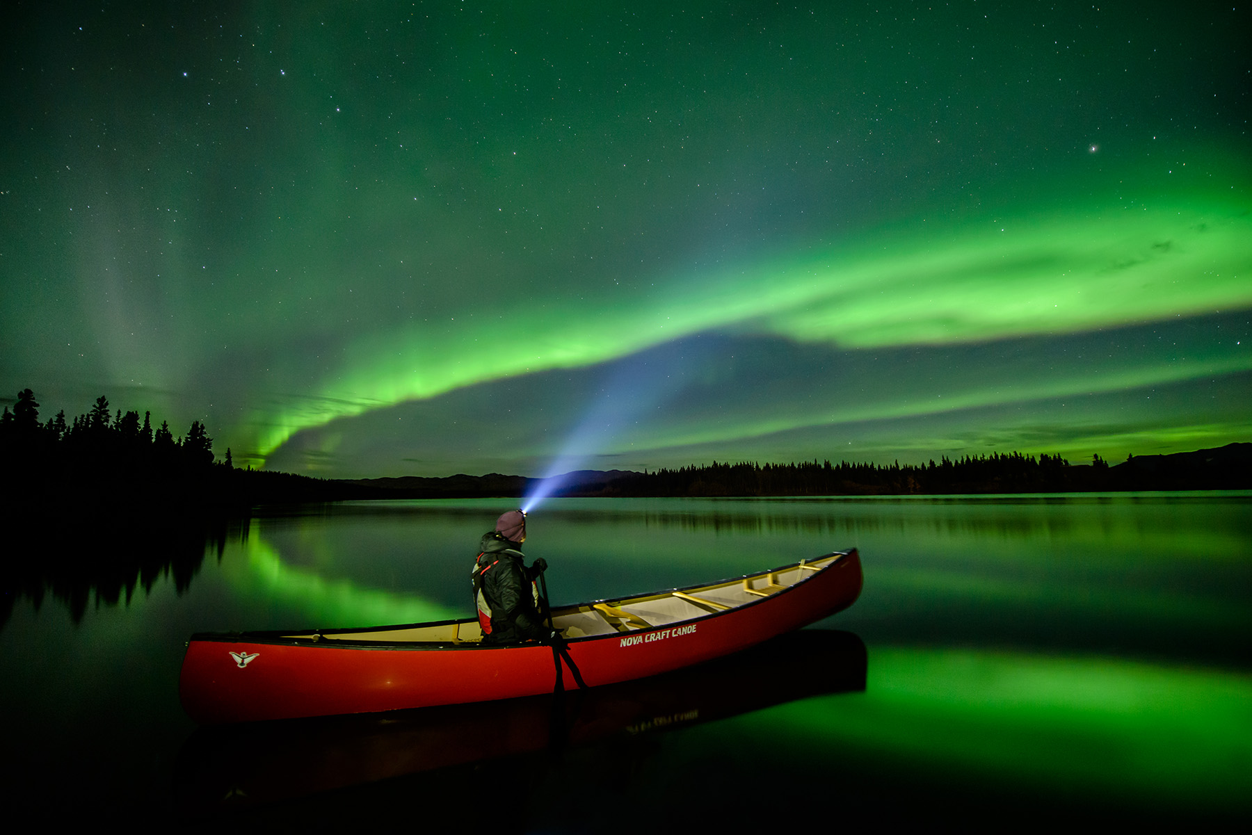 person in a canoe under the northern lights