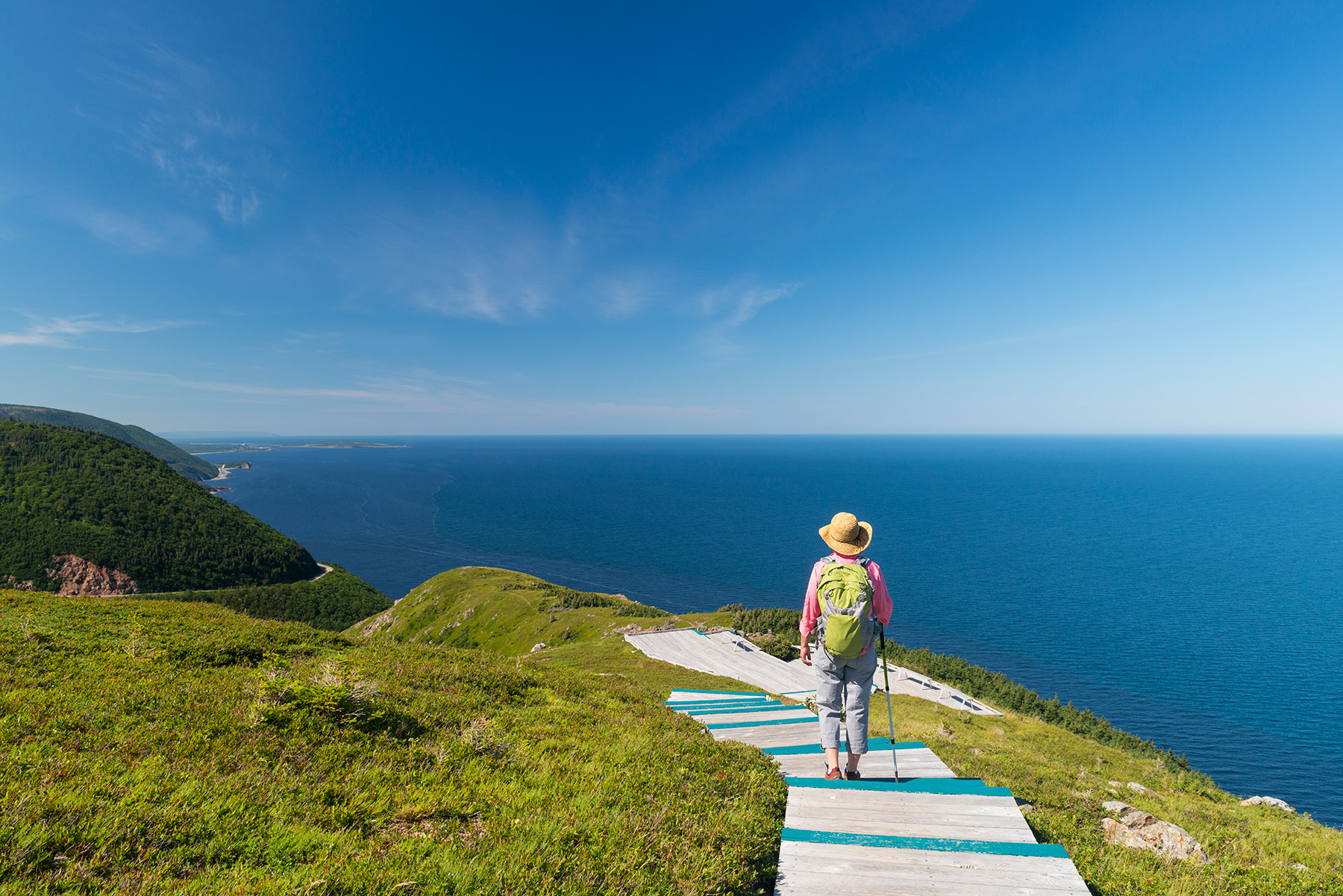 Perwon walking along a wooden track along the coast with a backpack