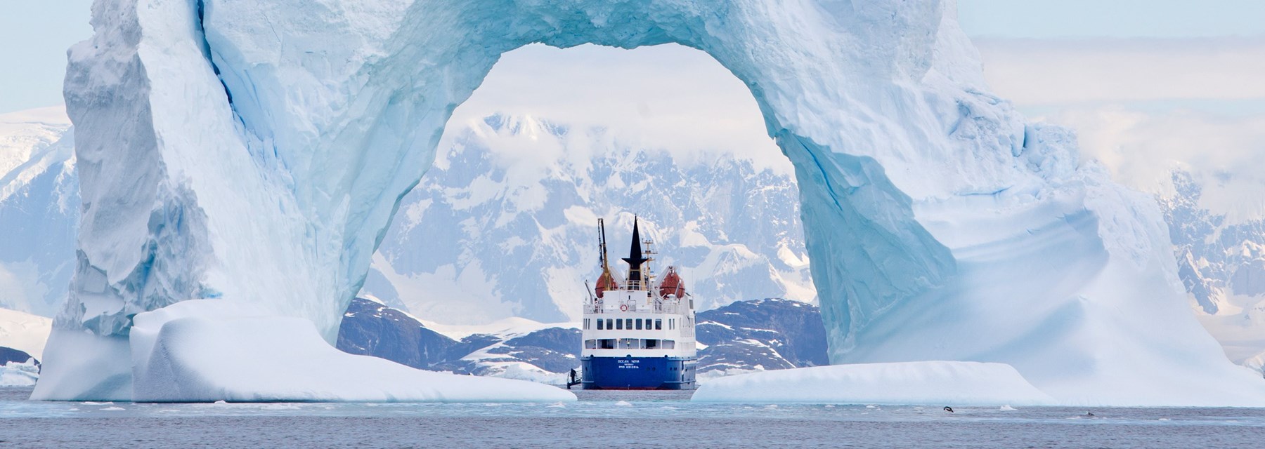 A boat in a body of water near an iceberg
