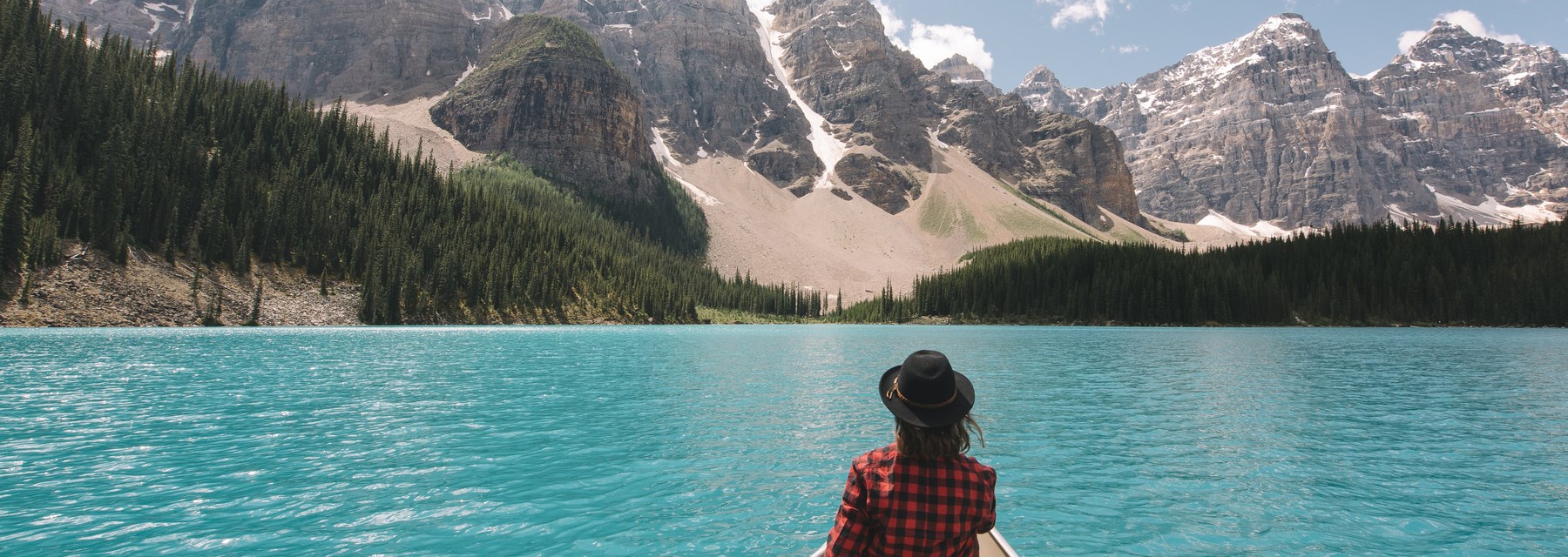 A person sitting on a boat in a lake looking at the Canadian Rockies