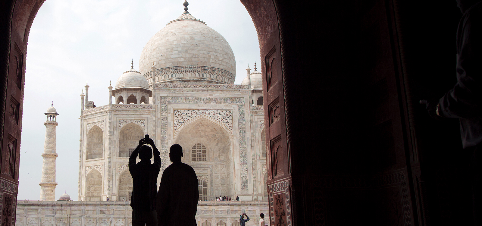 Two people photograph a building with a dome