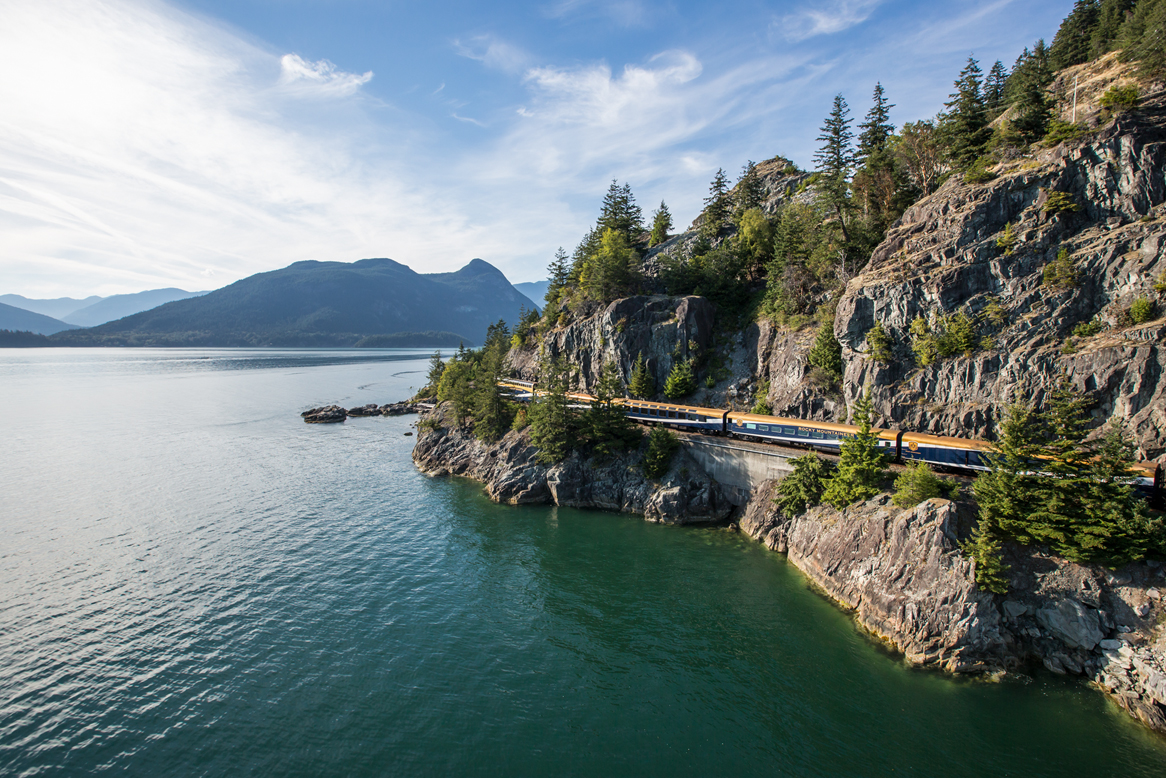 train along the coast at the base of a mountain