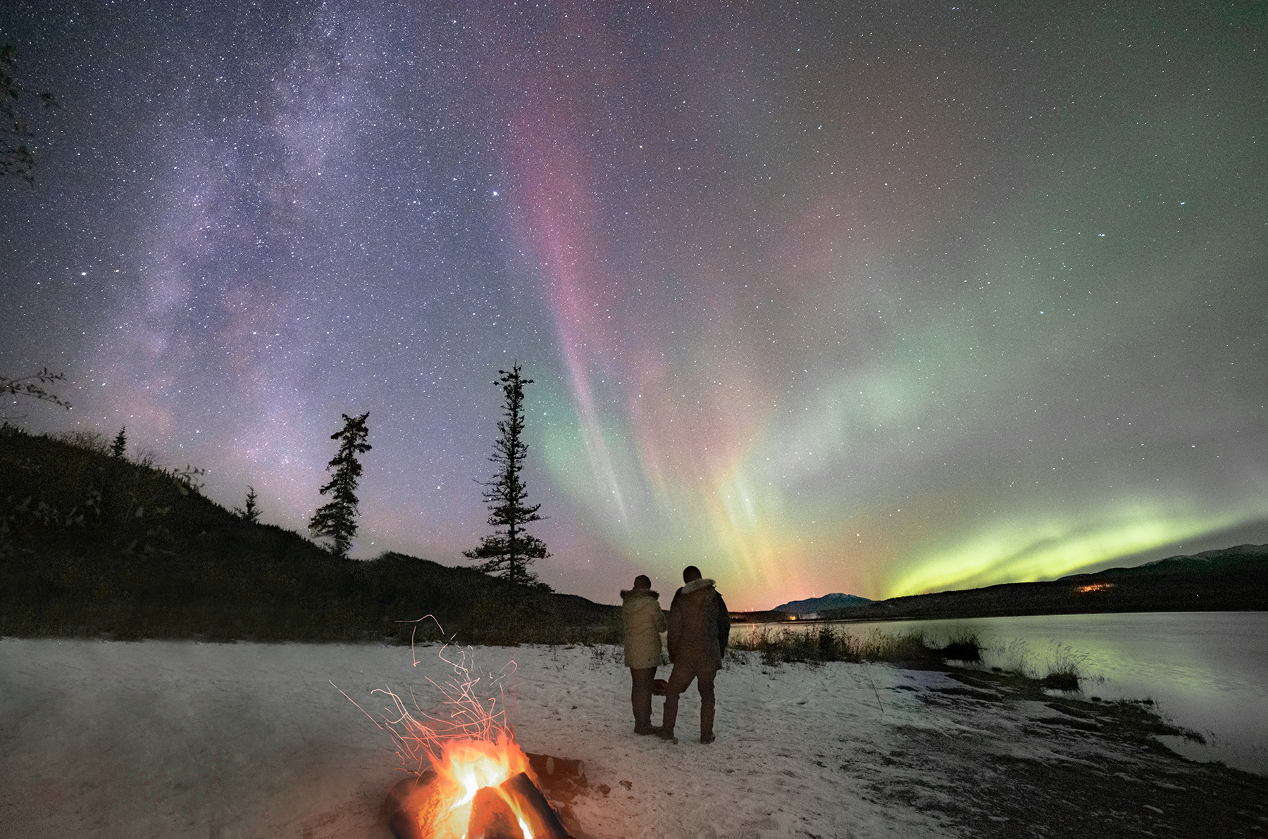 People looking up at northern lights in the snow