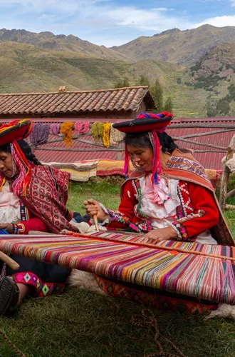 tHree Local Female Weavers In Colourful Traditional Local Dress Including Festooned Hats, Weaving Colourful Alpaca Wool On The Ground