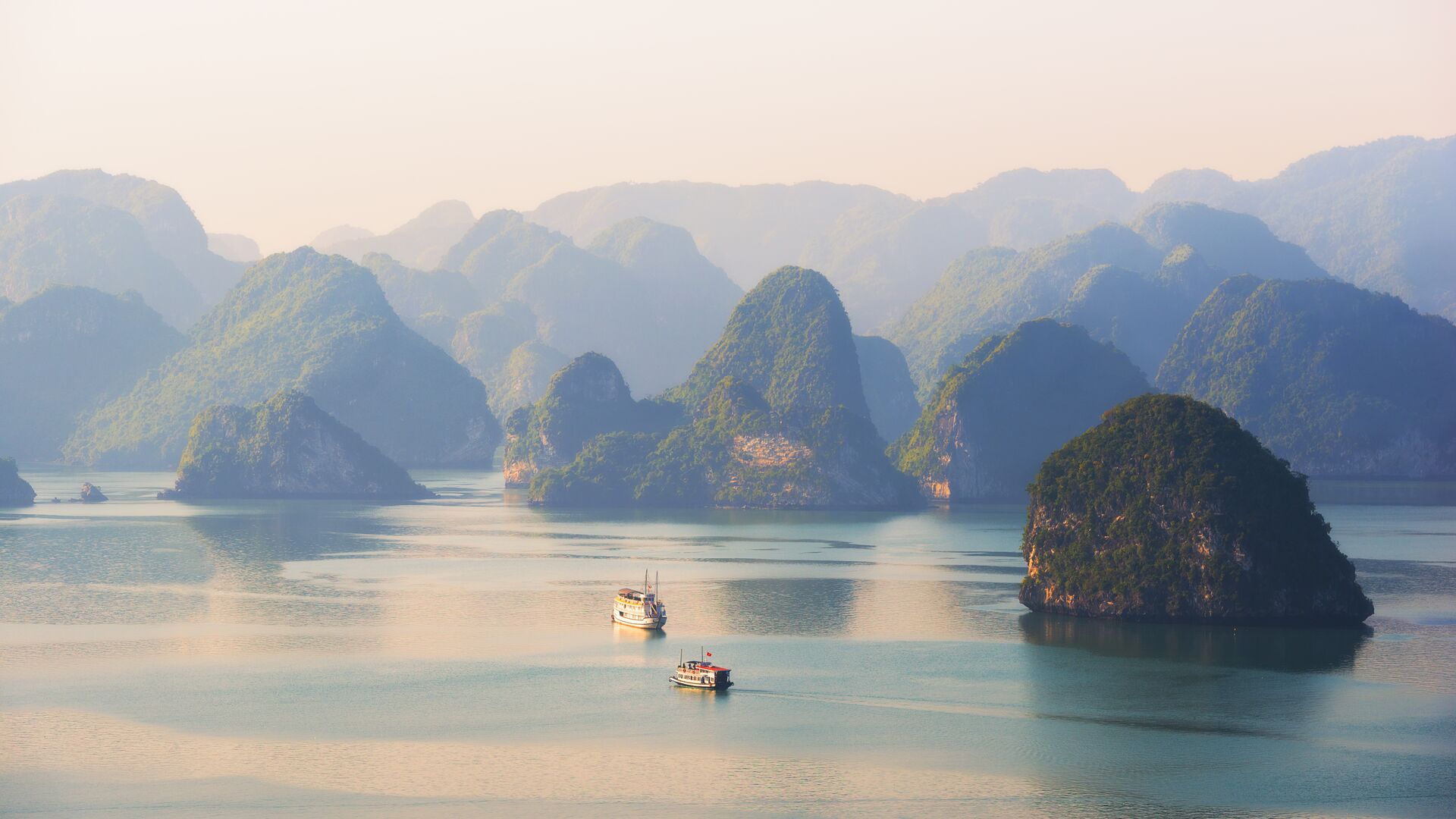 Junk boats within green rock formations in halong bay
