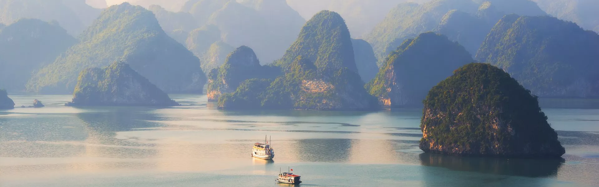 Junk boats within green rock formations in halong bay